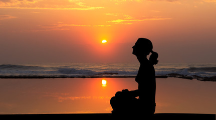 silhouette of a woman meditating at sunrisse