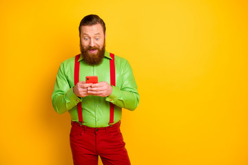 Portrait of astonished excited man blogger use cellphone read social network information impressed scream wow omg wear pants suspenders trousers isolated over yellow color background