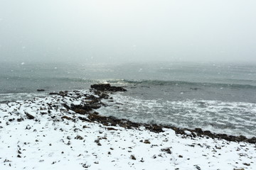 winter seascape evening on a stony snow covered shore