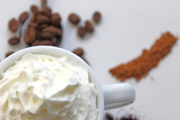 Closeup photo of espresso with whipped cream. In the background grains of coffee