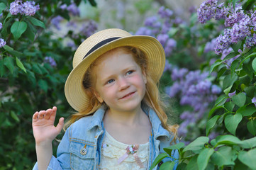 horizontal closeup portrait of a red-haired girl on a background of bushes of blooming lilac