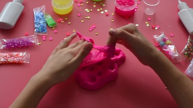 a girl making slime herself. child making slime on pink background.