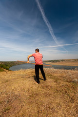 A man is engaged in curative gymnastics with a pole on the nature. Healthy lifestyle.