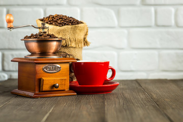 still life with coffee beans and old coffee mill on the wooden background,coffee grinder,coffee accessories brown clay cup vintage wooden mill and sack with beans scoop on old wood background