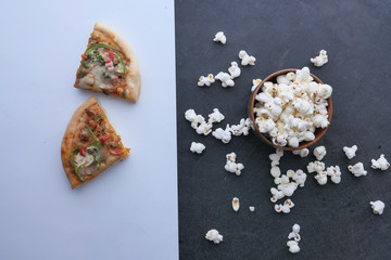 homemade pizza and popcorn in a bowl on table , top view