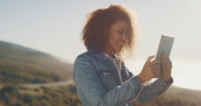 Young attractive african american woman taking pictures with her tablet outdoors in the afternoon, african american woman using technology and exploring the great outdoors