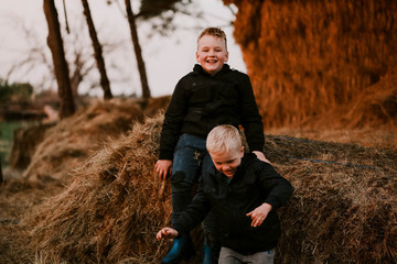 Brothers sitting together on haystack at winter time