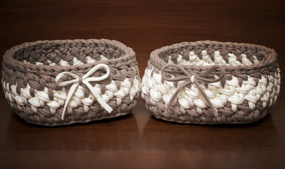 Two knitted baskets of handmade knitted yarn on a wooden background.