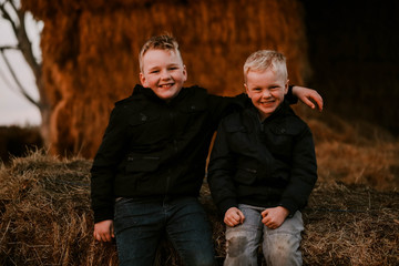 Brothers sitting together on haystack at winter time