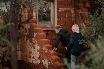Obraz na płótnie Canvas Two boys exploring ruins of fallen down mud brick house