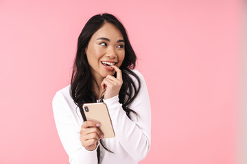 Image of young brunette asian woman with long hair holding cellphone