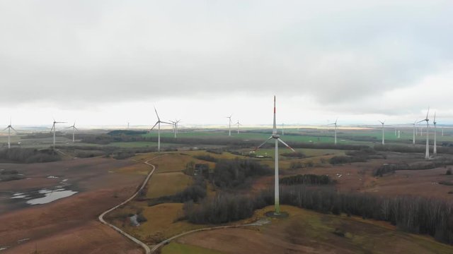 Evening aerial view over green energy and sustainable windmill farm field with rain clouds surrounded