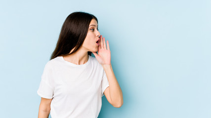 Young caucasian woman isolated on blue background is saying a secret hot braking news and looking...
