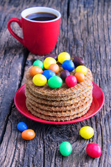 Colorful easter chocolate eggs with danish waffles and cup of coffee on wooden table