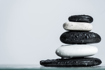 Close up view of water drops on stacked black and white zen stones on wet glass isolated on grey
