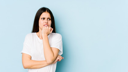 Obraz premium Young caucasian woman isolated on blue background biting fingernails, nervous and very anxious.