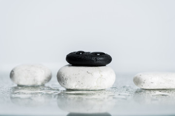 Back and white zen stones with water drops on wet glass on grey background