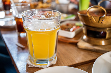 Craft beer with foam in big glass on wooden table in restaurant