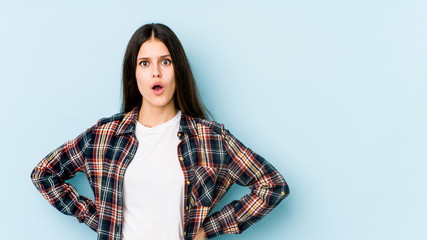 Young caucasian woman isolated on blue background being shocked because of something she has seen.
