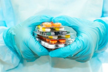 Nurse in a sterile gown and gloves holds packs of pills in blisters