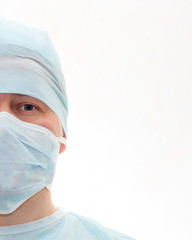 Half face portrait of surgeon in sterile surgical mask and medical cap