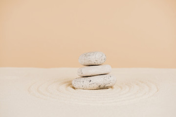 Fototapeta na wymiar Zen stones on sand with circles on beige background