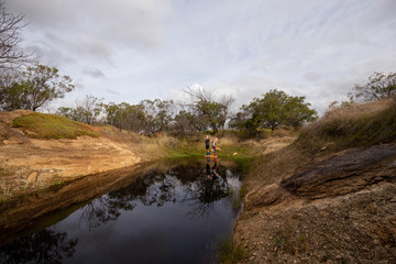 Two young boys catching tadpoles in natural waterhole