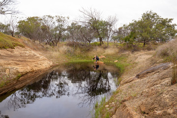 Young boy catching tadpoles in natural waterhole