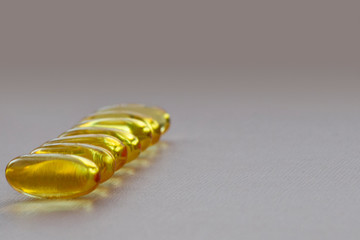 Bunch of omega 3 fish liver oil capsules forming line shaped pattern. Close up of big golden pills...