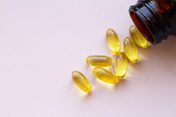 capsules of omega 3. a handful of pills spilling out of the jar