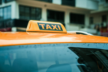 Close up yellow taxi sign on the roof of a car. Transport and travel concept. 