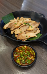 Thai style grilled pork slice serving with spicy chili dipping sauce