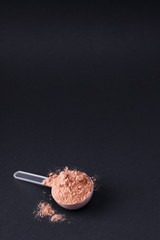 Scoop of chocolate whey protein in a black bowl. The concept of healthy eating and vitamins.