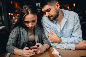 friends sitting in cafe using mobile phones