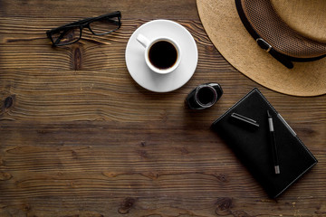 Blogger's work desk with hat and notebook on dark wooden background top-down copy space