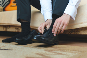 Fototapeta premium groom putting on black shoes