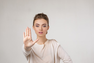 beautiful young woman making stop gesture on gray background.