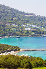 Beautiful bay with clear azure water and green palms. Beach on the territory of luxury Turkish hotel in Bodrum, Mugla, Turkey. Summer rich vacation. Travel concept