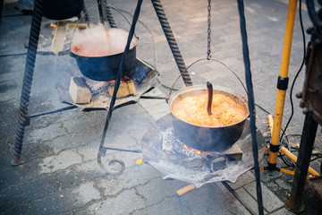 Metal soup bowls on open fire in outdoor event, street foood.