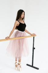 vertical photo on a white background of a young pretty ballerina with long dark hair