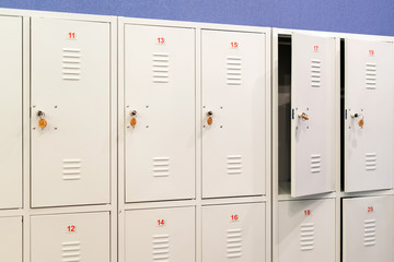 A row of grey metal school lockers with keys in the doors. Storage locker room in corridor of...