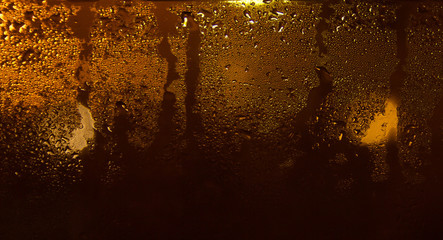Fuzzy background of water droplets on the window. Reflection of glare and light from lanterns. Background. Copy space. Water stains on the glass.