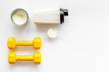 Sport nutrition. Whey protein, shaker, dumbbells on white background top-down flay lay copy space