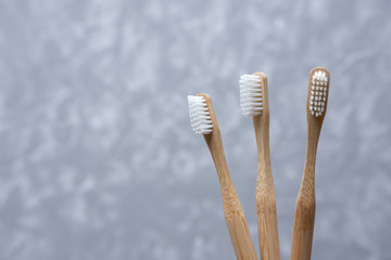Three white bamboo toothbrushes on a gray concrete background. soft light. friendly eco.