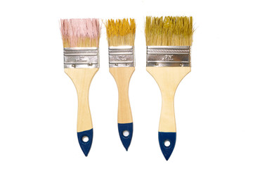 Three wide brushes with pink, yellow and green paint on them isolated on white background