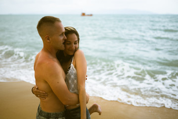 Fototapeta premium Beautiful guy and girl run and enjoy on the beach on the ocean or sea. Honeymoon in the tropics of a husband and wife. Romance in hot countries. Wallow in the sand and be happy and in love. Lovers