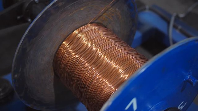 Copper wire unwinding from a spool. Closeup