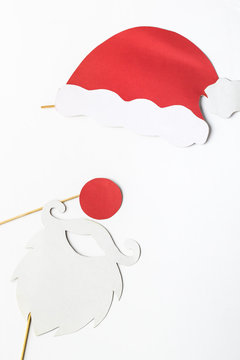 Festive Christmas decoration, white beard glasses and red Santas hat on sticks. accessories for party.