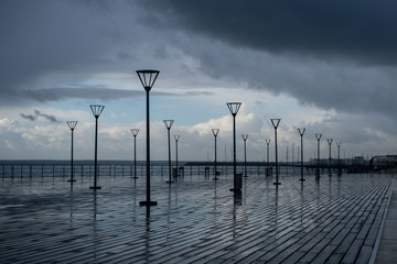 Lanterns on the embankment after rain and cloudy sky