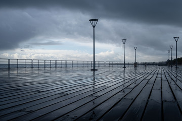 Naklejka premium Lanterns on the embankment after rain and cloudy sky